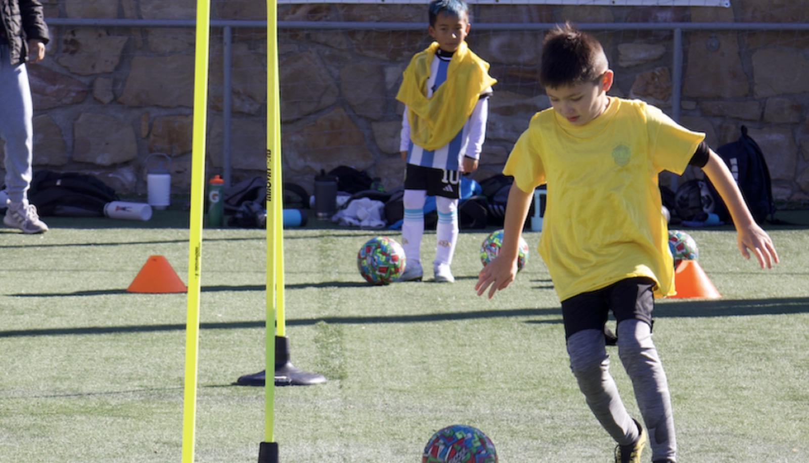 Young player dribbling through training poles